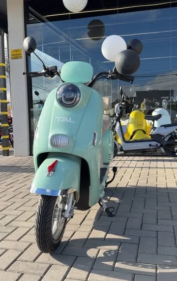 Scooter elétrica Retrô verde-menta da TAL em frente à loja